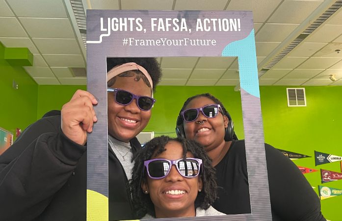  3 girls smiling with sunglasses holding a frame                                                